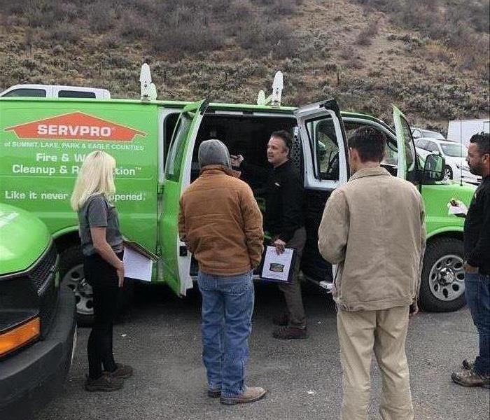 Employees standing outside a green SERVPRO van. 