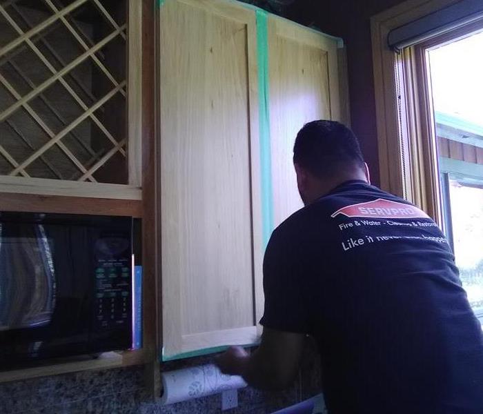 Employee measuring a cabinet. 
