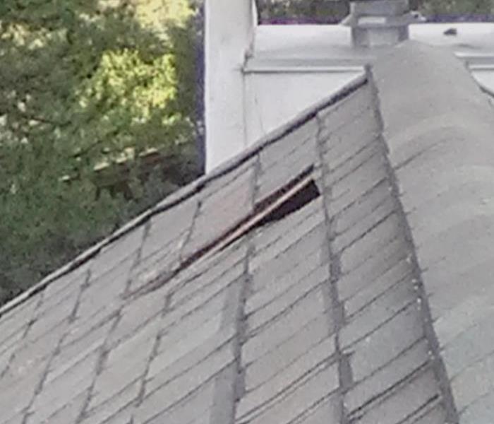 Grey roof has a hole from water damage. 