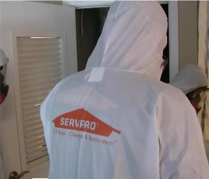 SERVPRO logo on the back of a man dressed in a PPE suit